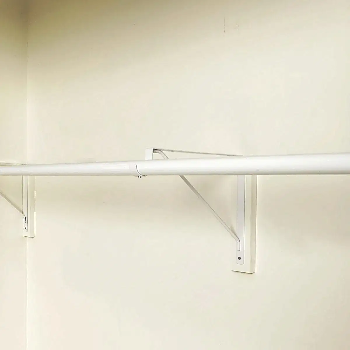 A Long white Rod For hanging Clothes on white wall